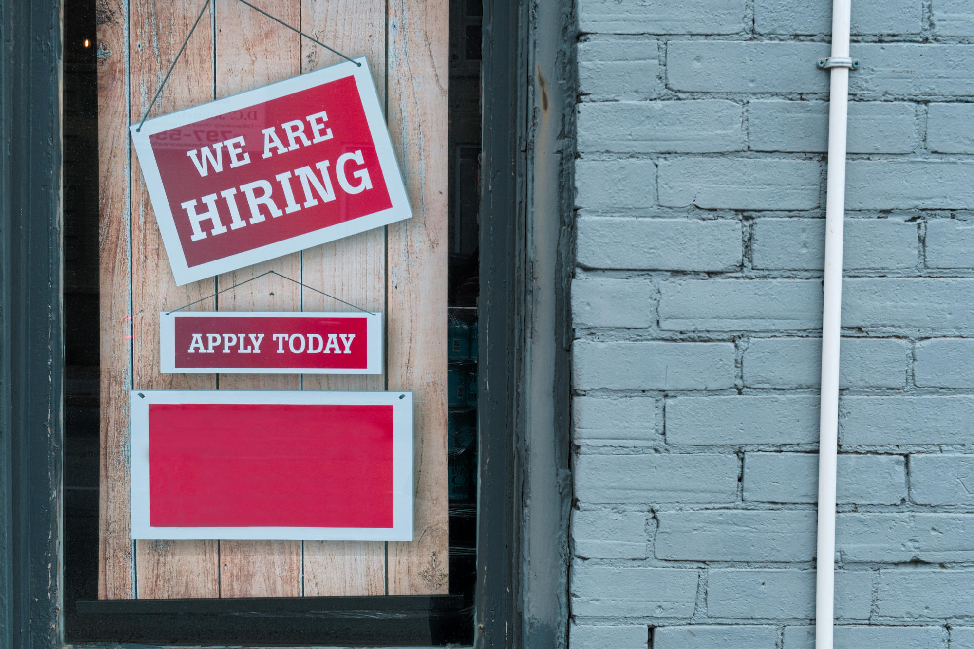Panneau "on recrute" (we are hiring) en vitrine.