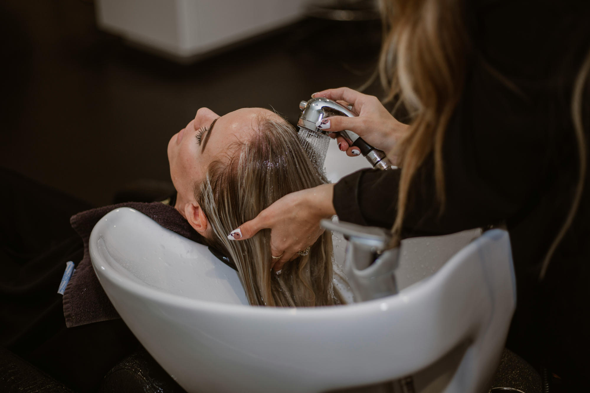 Une femme se fait laver les cheveux dans un salon de coiffure.